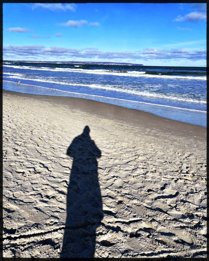 beach of the baltic sea with a long shadow of a person. 