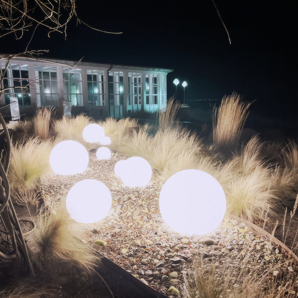 Some globes scattered on a beet of dry gras. the globes are illuminated as its dark night.