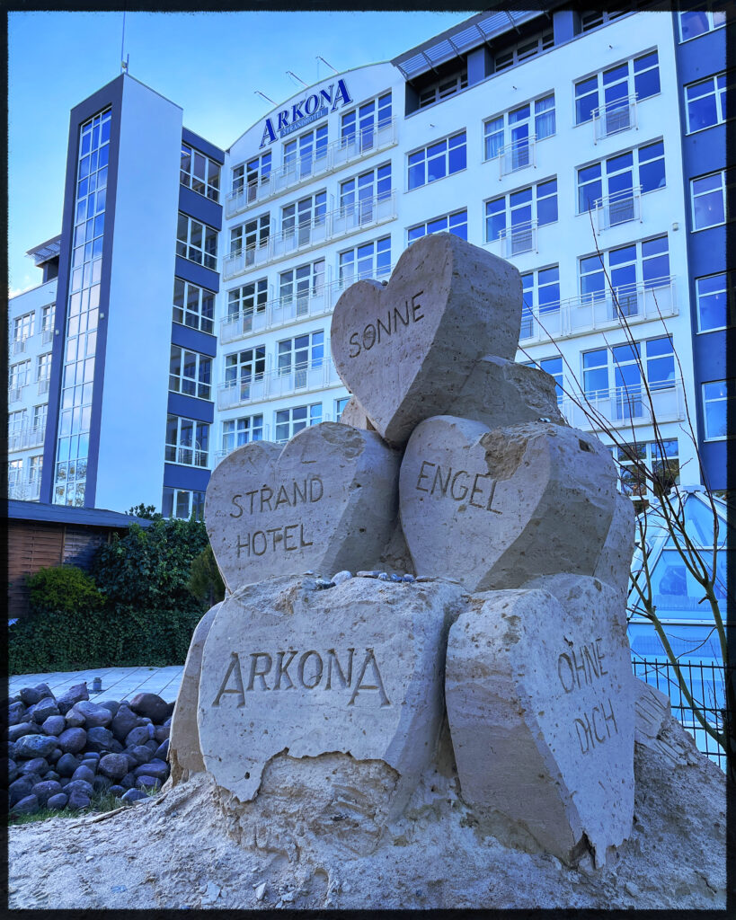 a sand sculpture showing 4 stacked hearts in front of an large hotel.
