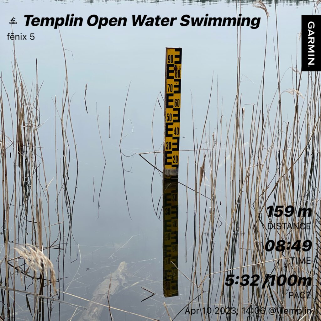 A water level gauge in a lake. A little bit of reed around. The picture has some stats printed on it from the Garmin app. Templin Open Water swimming  