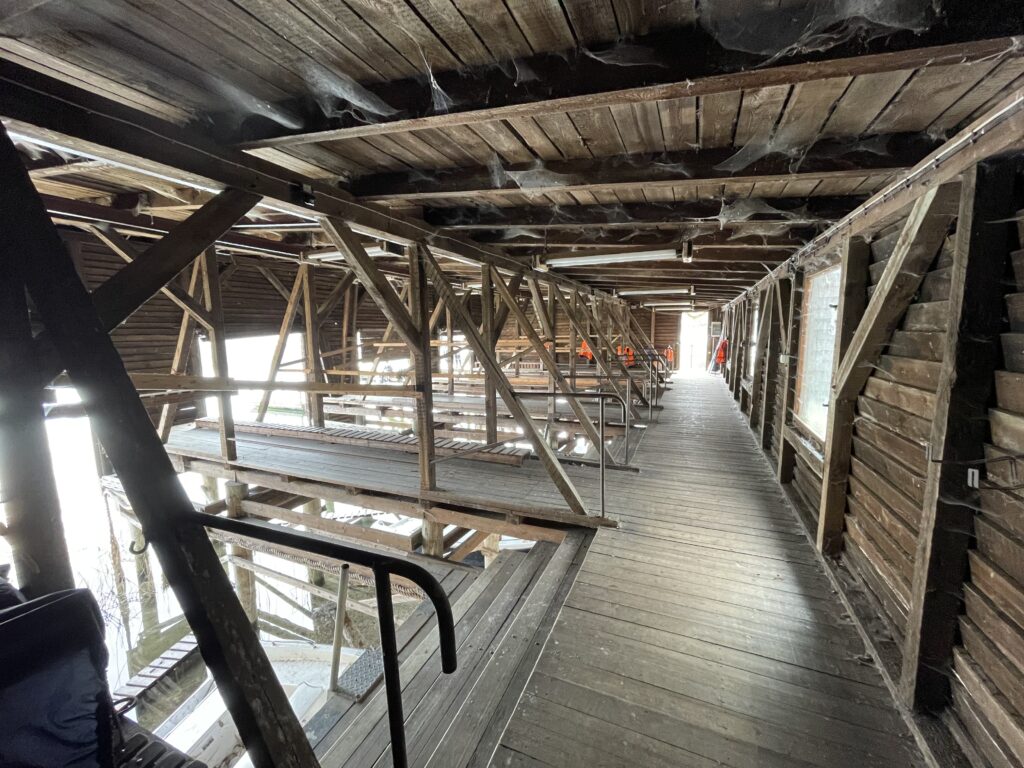 interior view of a wooden boat house on a lake. One can see stairs going to to the water 