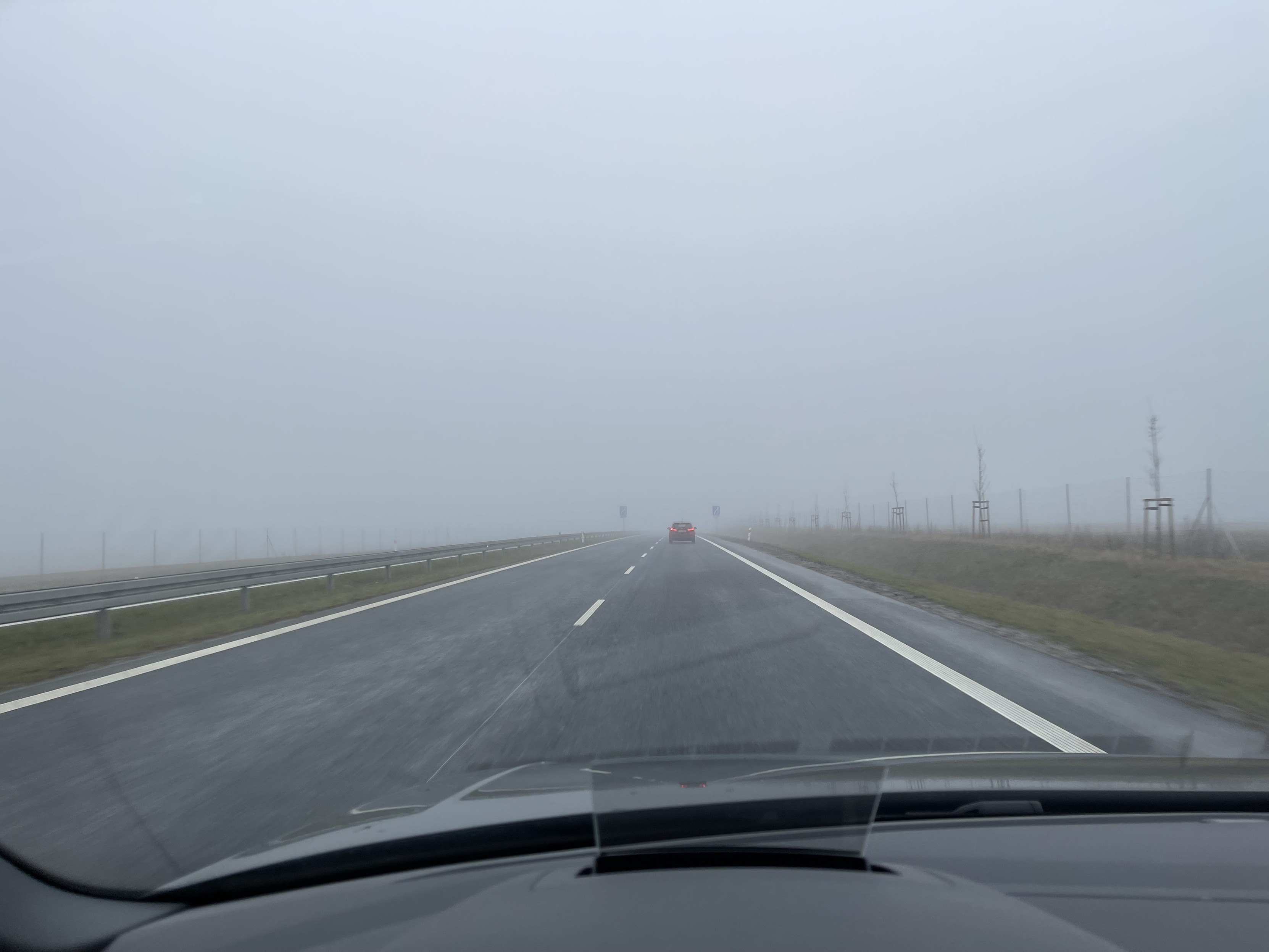 View from inside a car driving on a highway in foggy weather conditions.