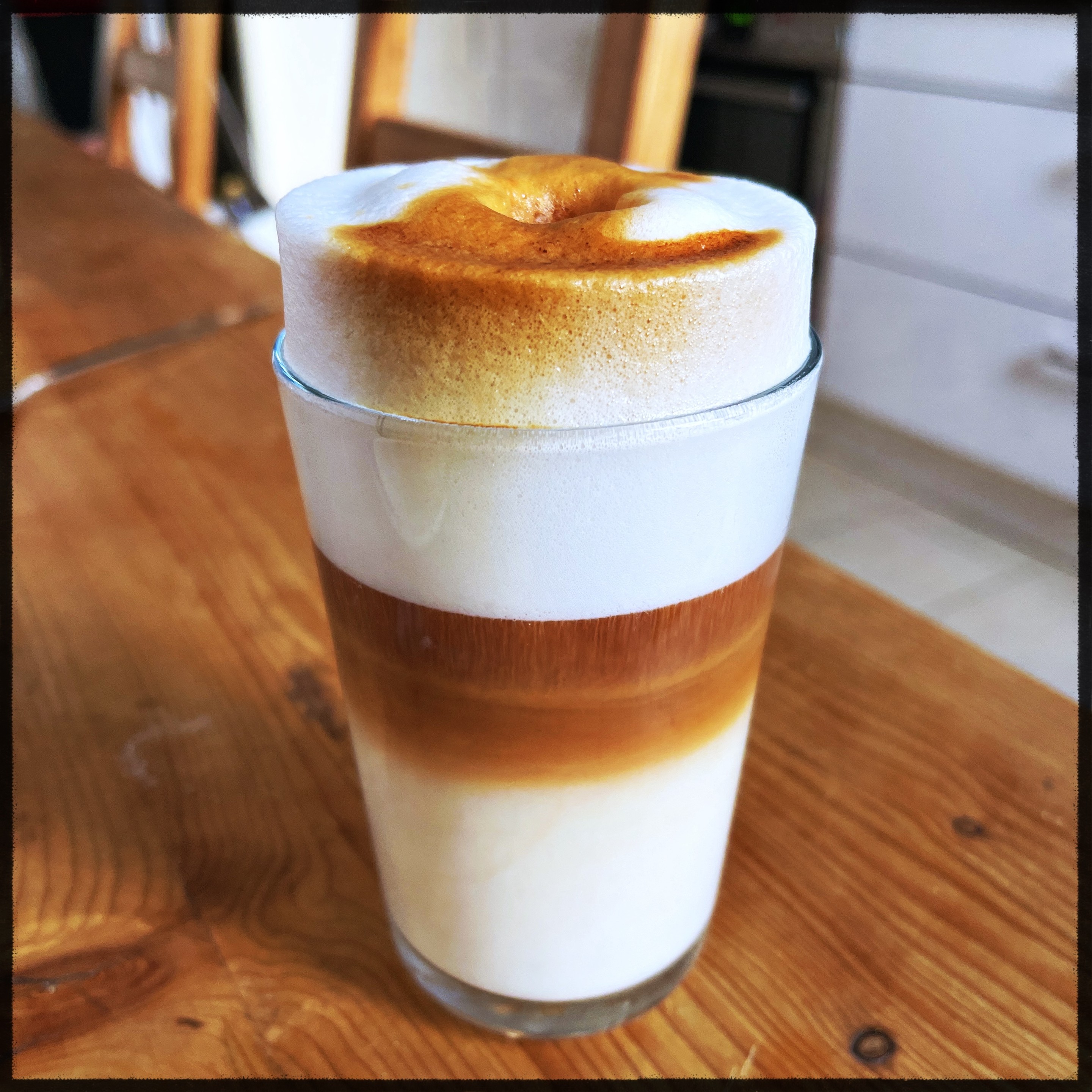 A glass full with frothed milk with a thick layer of orange redespresso in the middle. Redespresso is made rooibos tea. 