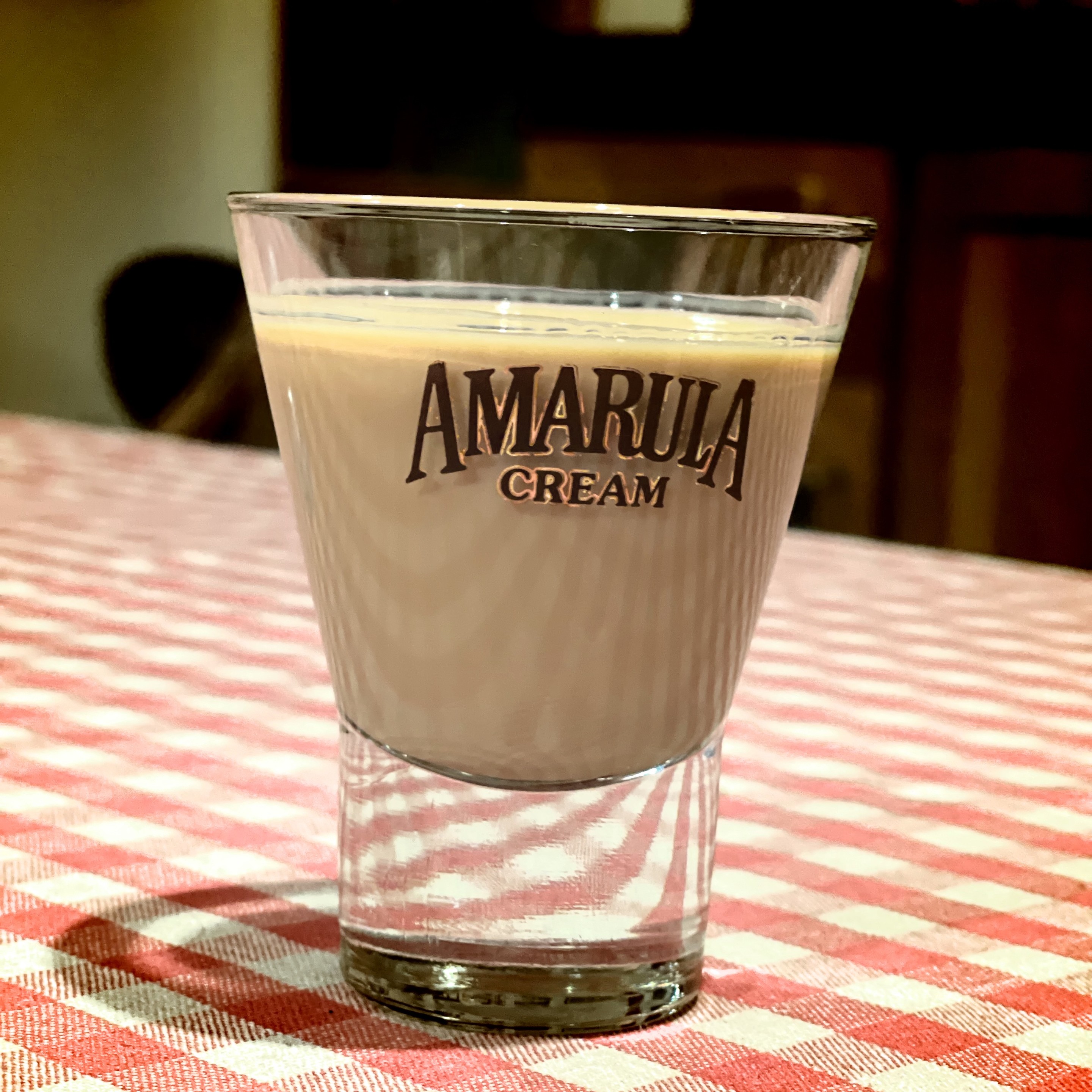 A glass of Amarula Cream liqueur on a checkered tablecloth.