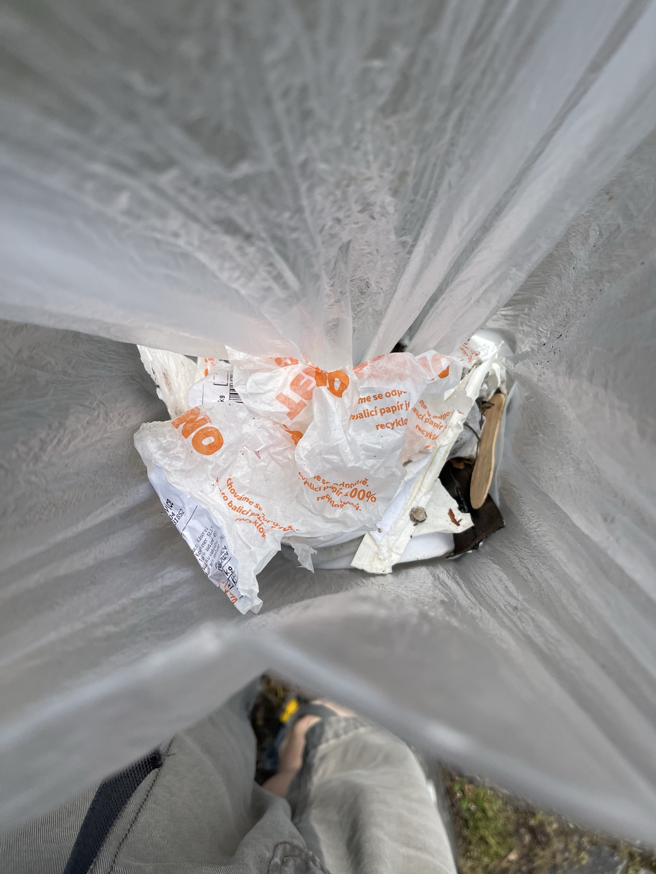Ein teilweise gefüllter Müllsack mit zerknitterten Papieren und anderem Müll. Das Bild wurde von oben aufgenommen.
